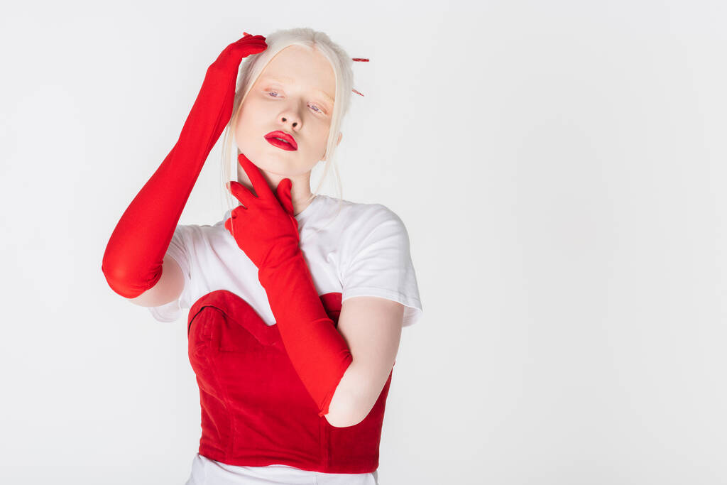 Albínský model s červenými rty a rukavicemi dotýkajícími se krku izolovaný na bílém - Fotografie, Obrázek