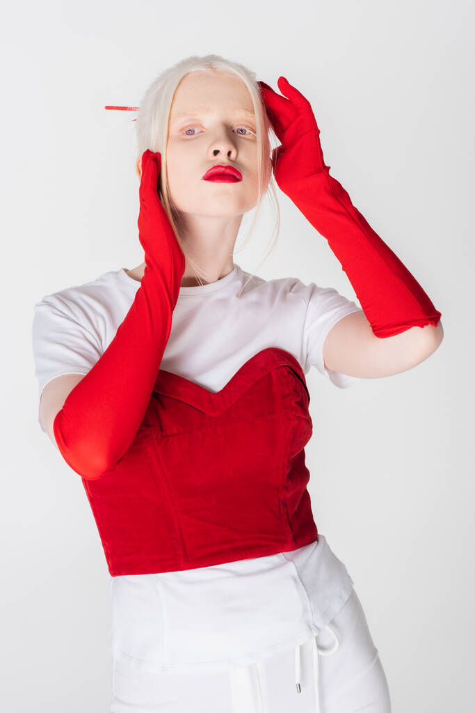 Modisches Albino-Modell in roten Handschuhen, isoliert auf weißem Grund stehend - Foto, Bild