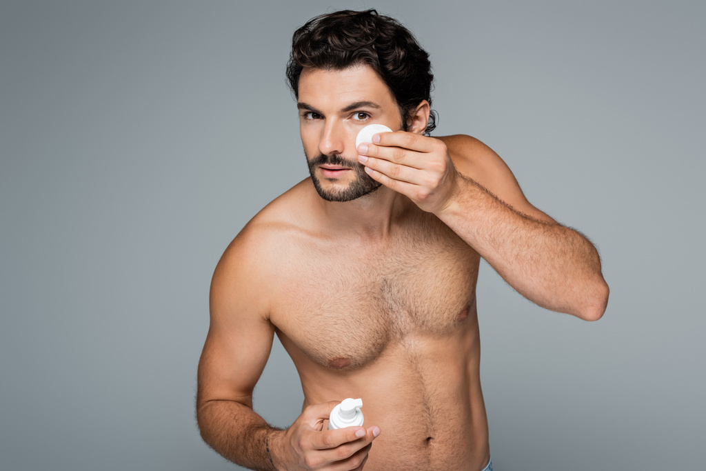 shirtless man applying toner on face with cotton pad isolated on grey - Photo, Image