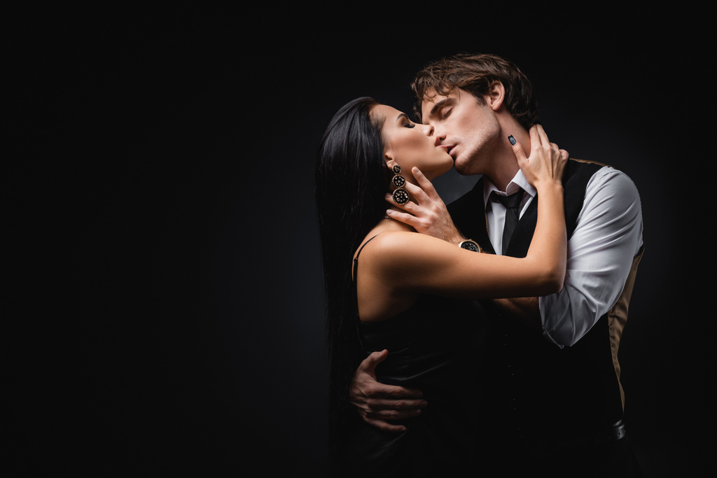uomo in gilet e camicia baciare fidanzata in seta slip dress su nero  - Foto, immagini