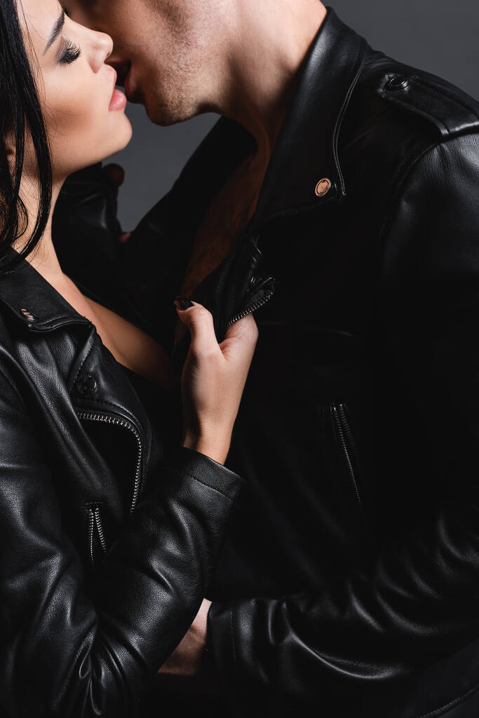 szexi fiatal pár bőrdzsekiben csók elszigetelt szürke - Fotó, kép