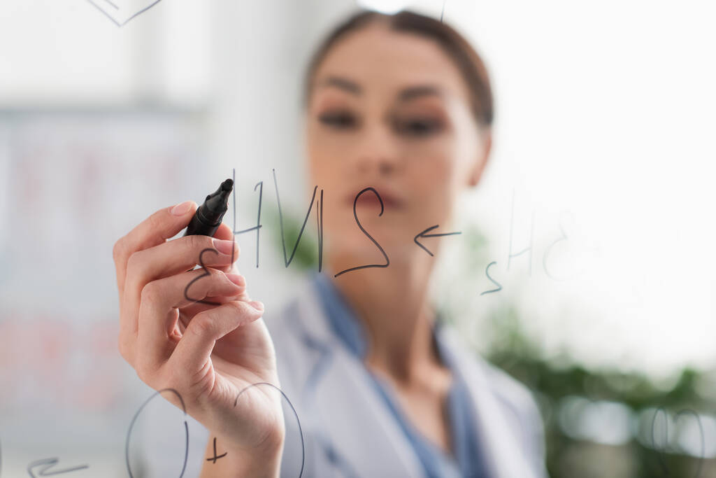médico desfocado com caneta de feltro escrever fórmulas químicas em placa de vidro - Foto, Imagem