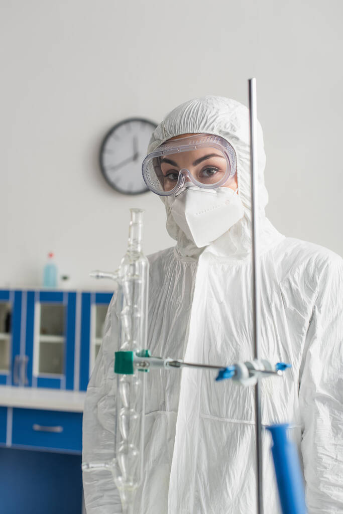 médico en traje de materiales peligrosos y gafas mirando a la cámara en el laboratorio - Foto, Imagen