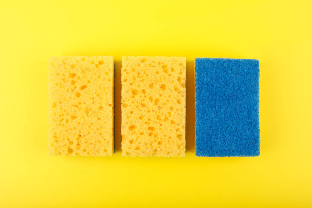 Close-up van drie gele reinigingssponzen op felgele achtergrond - Foto, afbeelding