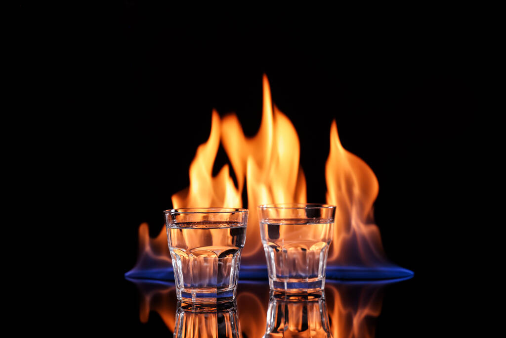Vodka in bicchieri e fiamma su sfondo nero - Foto, immagini