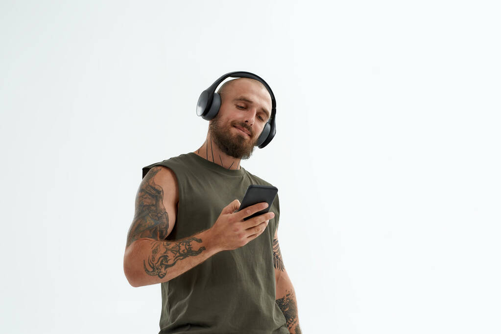 Mies kuunnella musiikkia kuulokkeet ja käyttää älypuhelinta - Valokuva, kuva