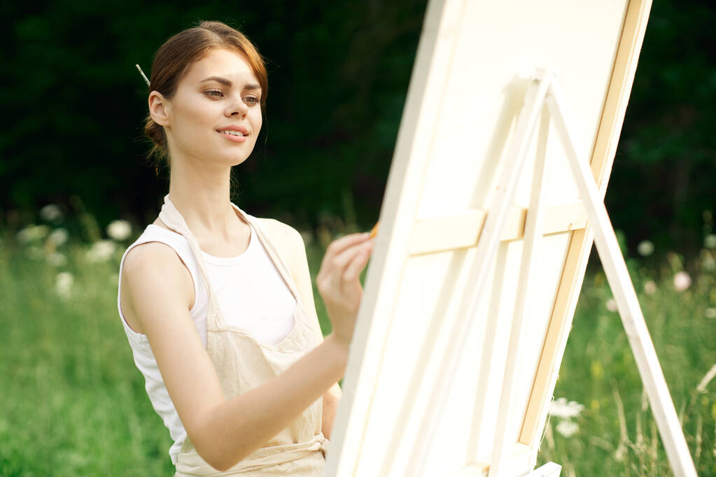 mujer artista pinta un cuadro cerca caballete al aire libre paisaje creativo - Foto, Imagen