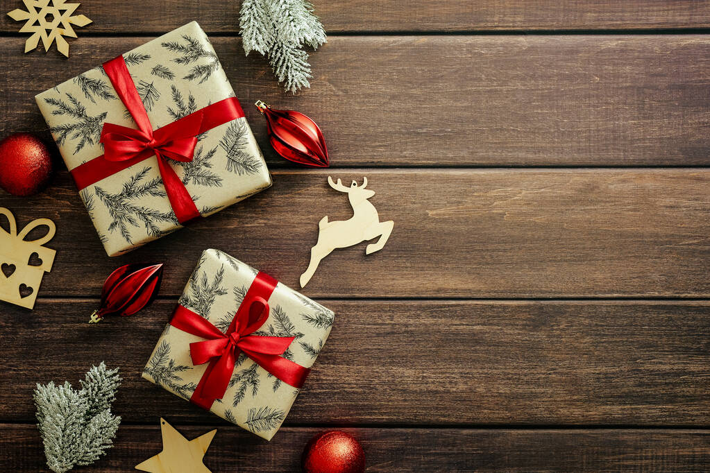 Rústicas cajas de regalo de Navidad decoradas con lazo de cinta roja. decoraciones de madera, ramas de abeto en la mesa de madera. Asiento plano, vista superior. Diseño de postal de Navidad. - Foto, imagen