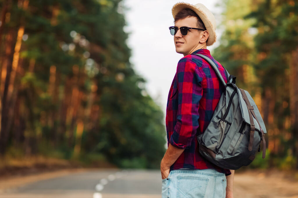 Portré egy kalapos turistáról, aki az erdőben sétál. Erős sportos ember utazó hátizsák erdei háttér - Fotó, kép