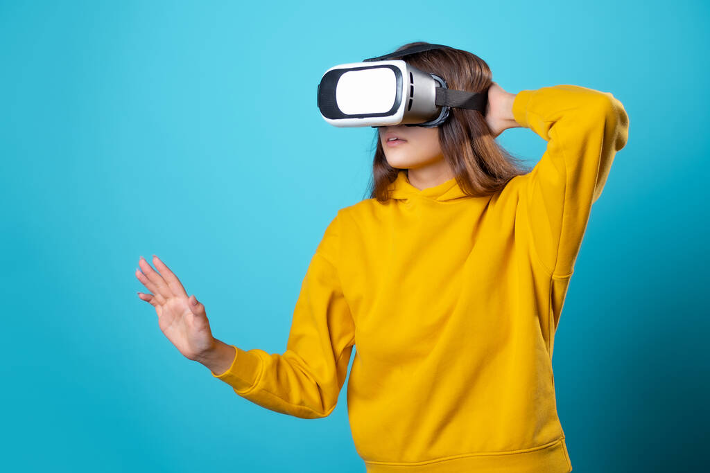 VR hráč, mladá žena v mladém oblečení používá helmu virtuální reality. - Fotografie, Obrázek