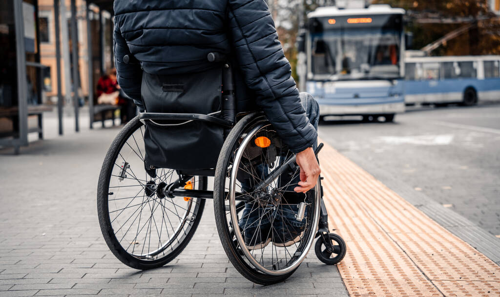 Persona con discapacidad física que espera el transporte urbano con una rampa accesible. - Foto, imagen