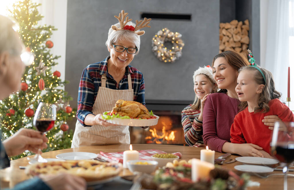 メリークリスマス幸せな家族は家で夕食を食べている。ツリーの近くでお祝いの休日と団結. - 写真・画像