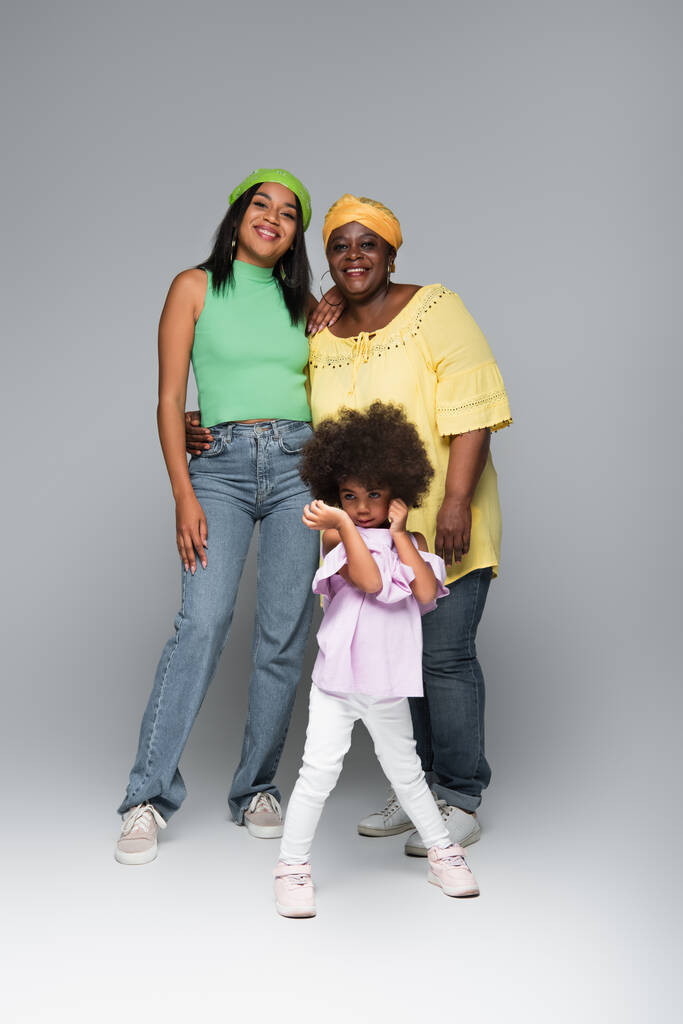 heureux et élégant afro-américain femmes posant près de tout-petit fille sur gris - Photo, image