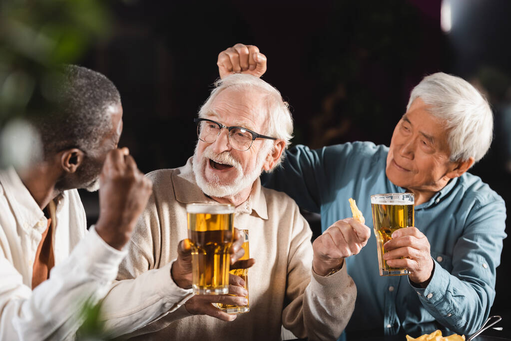 Neşeli, yaşlı, etnik çeşitlilikte erkekler barda vakit geçirirken bira içiyorlar. - Fotoğraf, Görsel