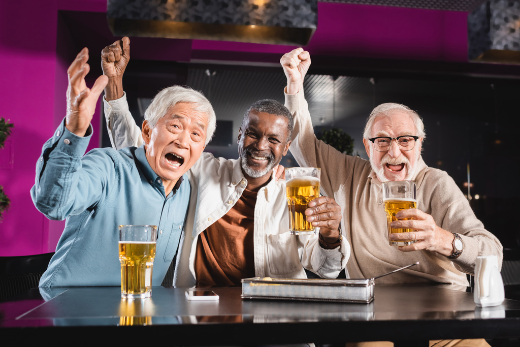 ενθουσιασμένοι ηλικιωμένοι πολυεθνικοί φίλοι δείχνουν θριαμβευτική χειρονομία βλέποντας ποδόσφαιρο πρωτάθλημα στην παμπ - Φωτογραφία, εικόνα