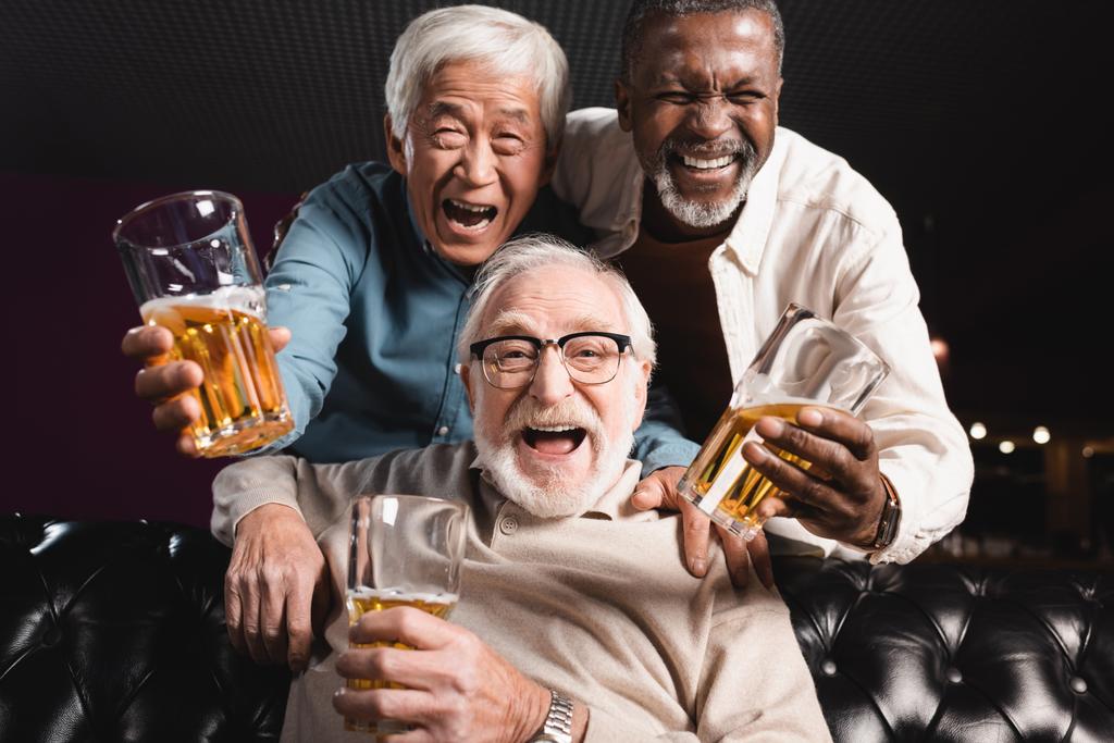 amigos ancianos con vasos de cerveza riendo en la cámara en el pub - Foto, imagen