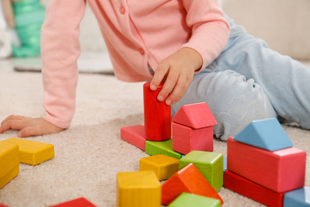Мила дівчинка грає з барвистими будівельними блоками в приміщенні, крупним планом
 - Фото, зображення