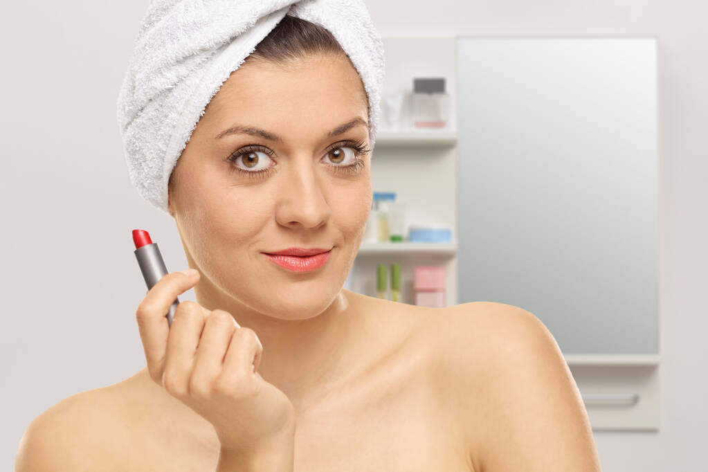 Młoda kobieta trzyma czerwoną szminkę w łazience - Zdjęcie, obraz