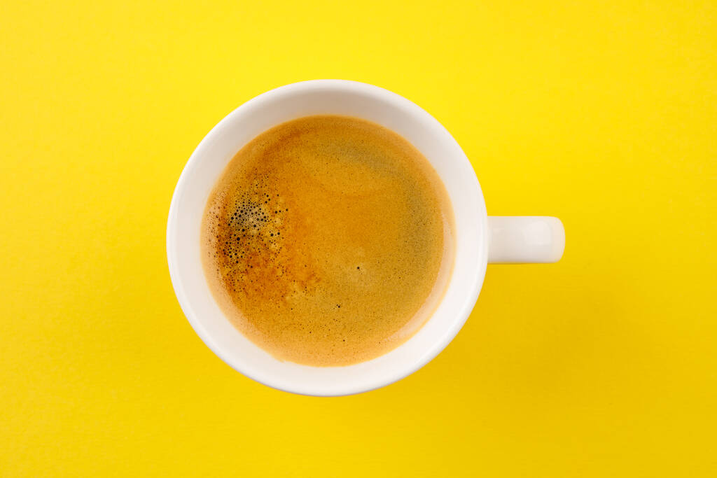 Schwarzer Kaffee in einer Tasse auf gelbem Hintergrund - Foto, Bild