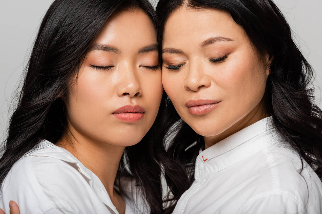 asiatische Mutter und junge erwachsene Tochter in weißen Hemden isoliert auf grau - Foto, Bild