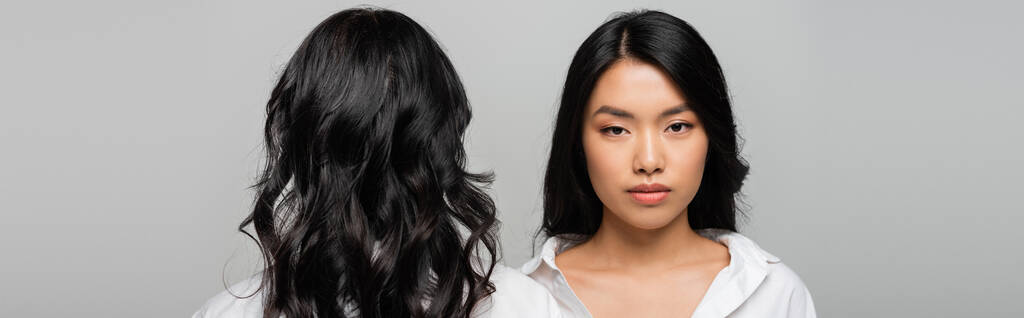 vue arrière de brunette asiatique mère près de jeune adulte fille isolé sur gris, bannière - Photo, image