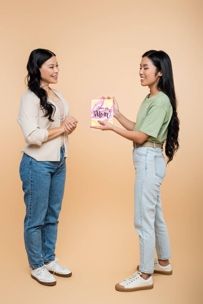feliz asiática mujer dando tarjeta de felicitación con i love you mamá lettering a madre en beige  - Foto, Imagen