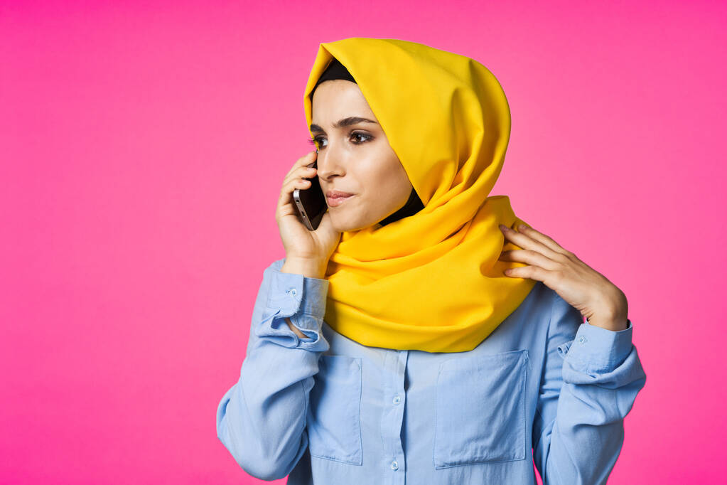 Moslim vrouw dragen hijab telefoon communicatie technologie roze achtergrond - Foto, afbeelding