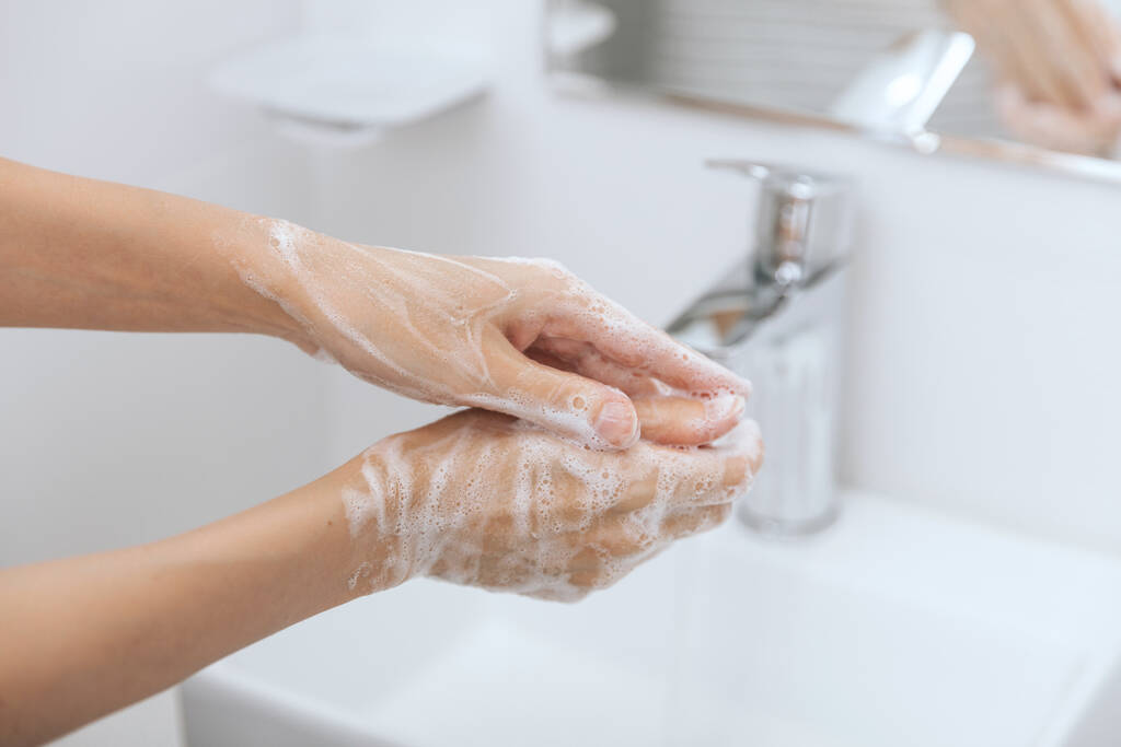 流れる水の下で手を洗う。衛生コンセプトの手の詳細。手を洗うには、コロナウイルスの予防、コロナウイルスの拡散を停止する衛生、または公共の洗面所の石鹸でこすり - 写真・画像