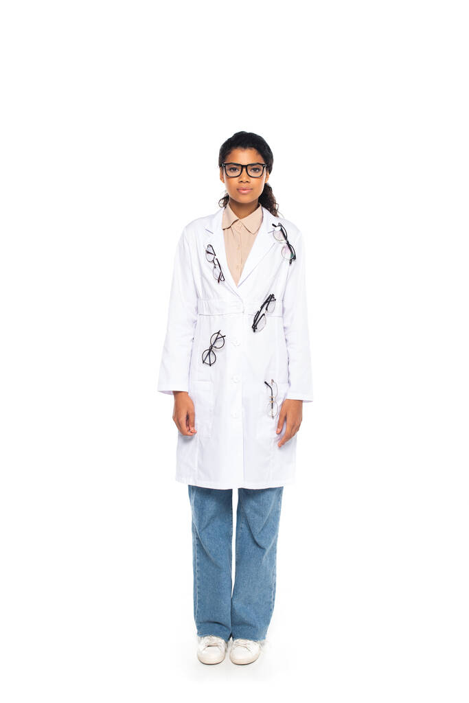 Pleine longueur de jeune oculiste afro-américain en lunettes sur manteau sur fond blanc - Photo, image