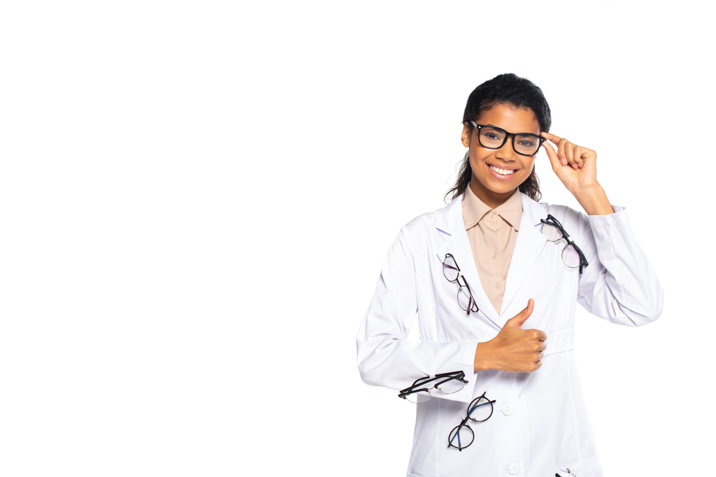 Usmívající se afro-americký oftalmolog s brýlemi ukazujícími jako znamení izolované na bílém  - Fotografie, Obrázek