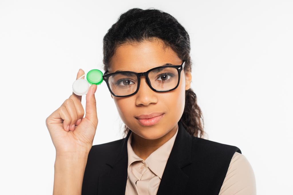 Portret van een Afrikaans-Amerikaanse zakenvrouw in een bril met een container met contactlenzen geïsoleerd op wit  - Foto, afbeelding