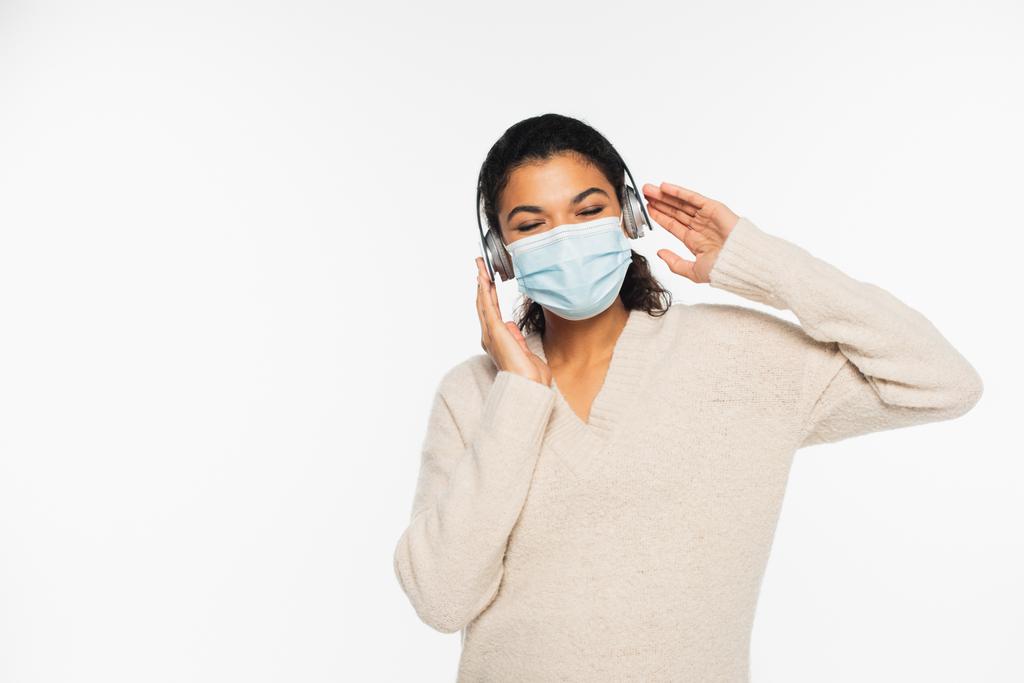 Donna afroamericana in maschera medica e cuffie isolate su bianco - Foto, immagini