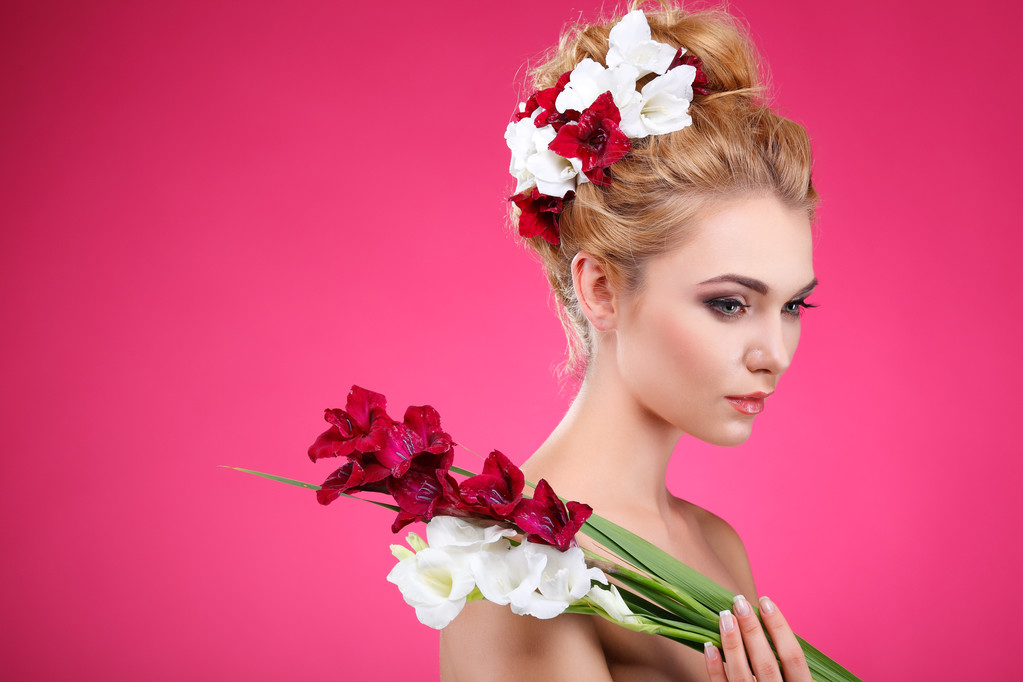 schönes Mädchen, isoliert auf rosa Hintergrund mit bunten Blumen in Haaren, Emotionen, Kosmetik - Foto, Bild