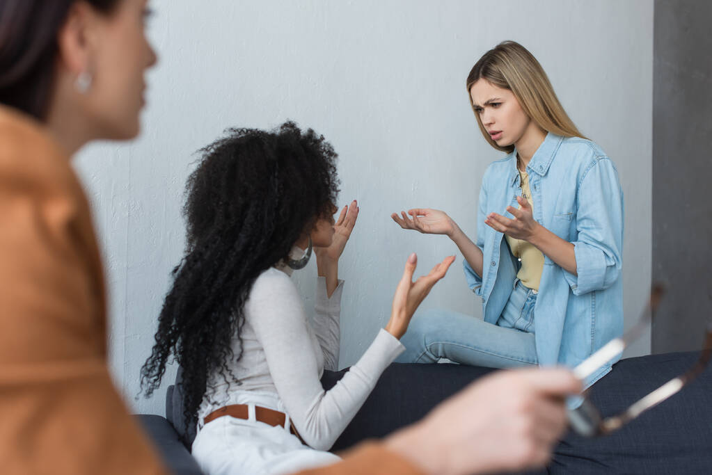 interracial lesbiana pareja peleando cerca borrosa psicólogo en consultoría - Foto, imagen