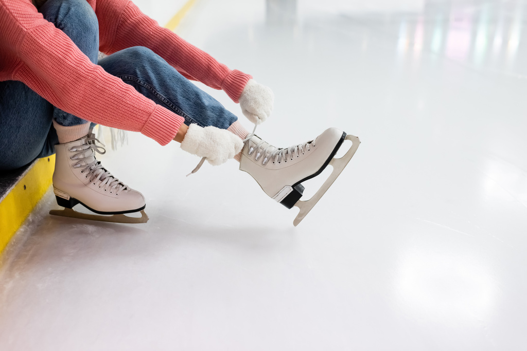 氷の上で靴のレースを結ぶ若い女性の部分的なビュー - 写真・画像