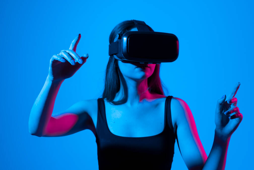 Jonge creatieve zakenvrouw, IT-ontwikkelaar, ontwerper met VR virtual reality bril en gebaar in de virtuele wereld. Virtual reality 3d-technologieën. - Foto, afbeelding