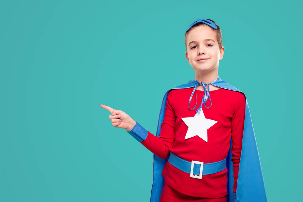Усміхнена супергеройська дитина вказує геть
 - Фото, зображення