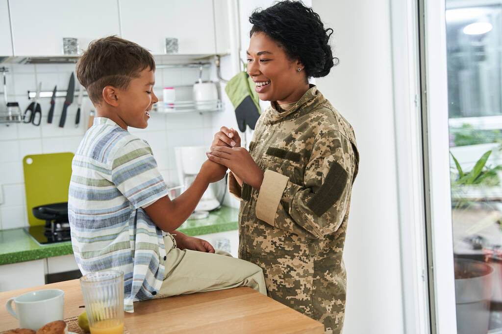 Schwarze Soldatin hält Hand ihres Sohnes - Foto, Bild