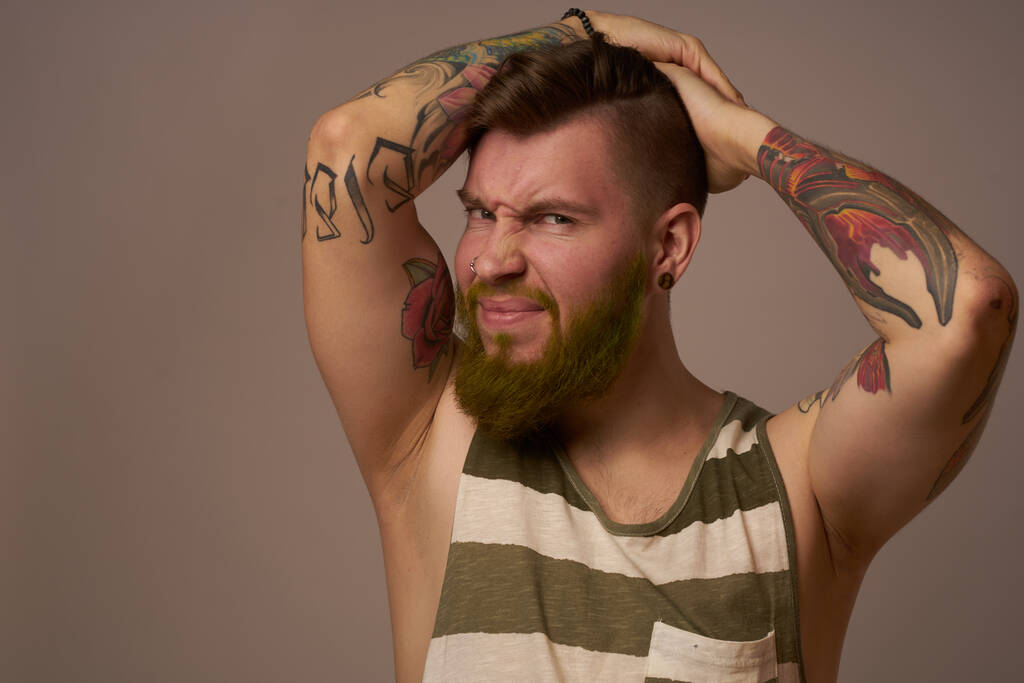 schöner Mann mit Tätowierungen auf den Armen modische Frisur Emotionen - Foto, Bild