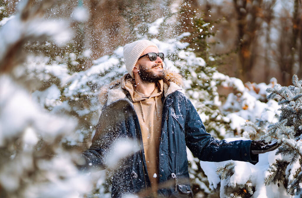 Ritratto di giovane uomo nella foresta invernale innevata. Stagione, Natale, viaggio e concetto di persone. - Foto, immagini
