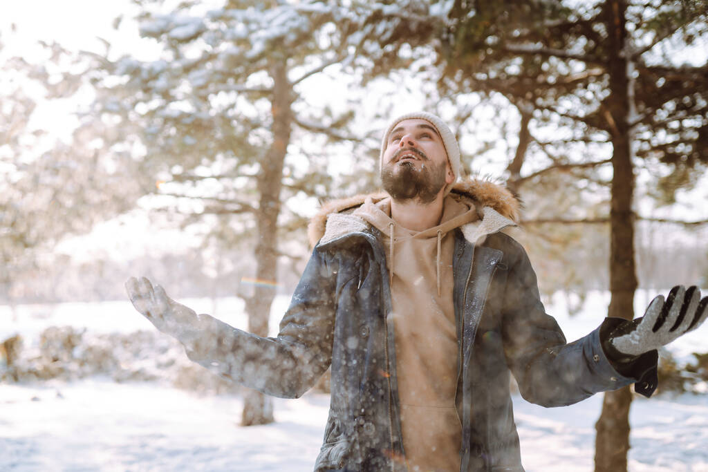 Πορτρέτο του νεαρού άνδρα στο χιονισμένο δάσος του χειμώνα. Εποχή, Χριστούγεννα, ταξίδια και άνθρωποι έννοια. - Φωτογραφία, εικόνα