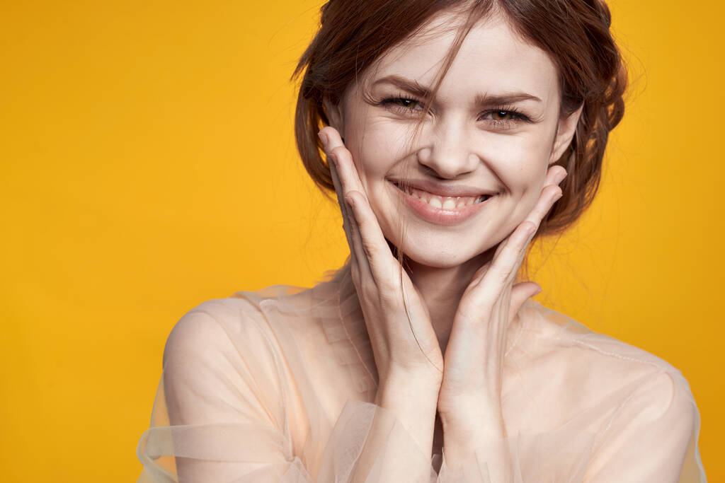 portré egy nő gesztus kéz kozmetikumok divat frizura pózol sárga háttér - Fotó, kép