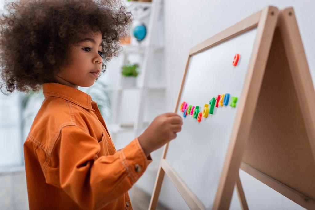 Toddler african american kid standing near magnetic board with numbers at home  - Photo, Image