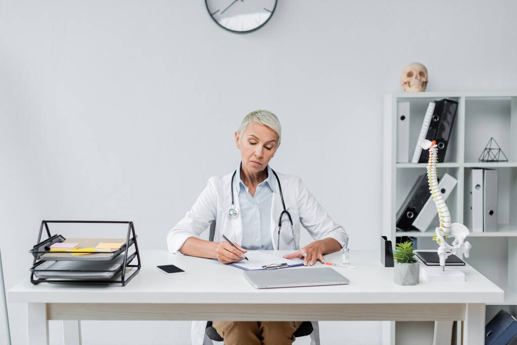 médico senior en la prescripción de la bata blanca cerca de dispositivos en el escritorio  - Foto, Imagen