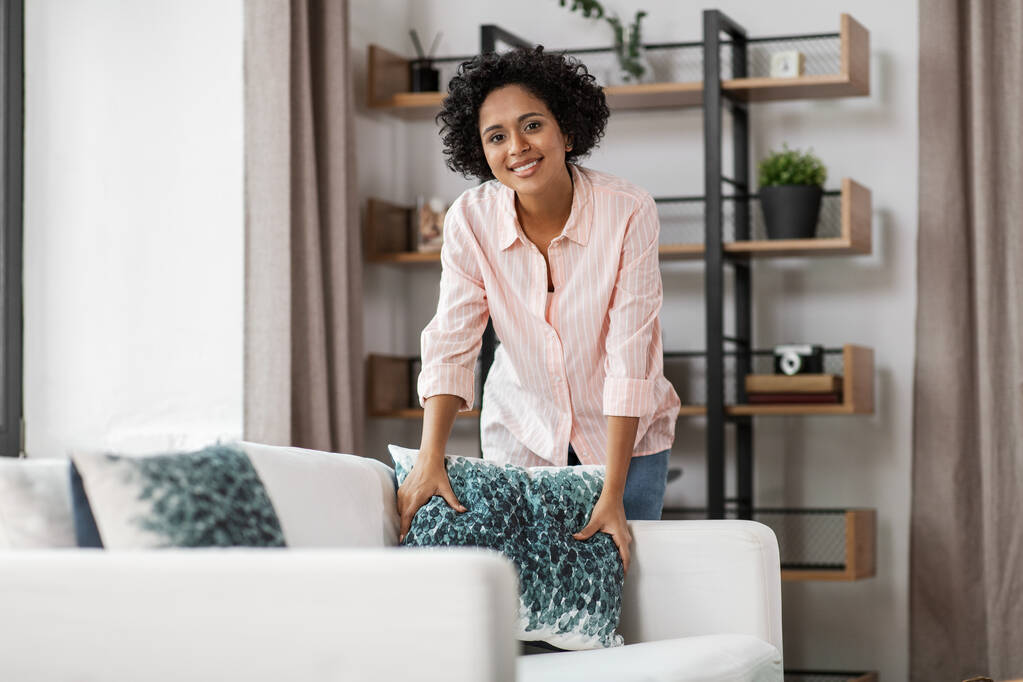 щаслива жінка влаштовує подушки на дивані вдома
 - Фото, зображення