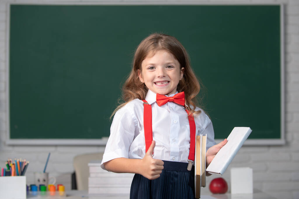 Aranyos, kedves, iskolai egyenruhás lány portréja az osztályteremben. - Fotó, kép