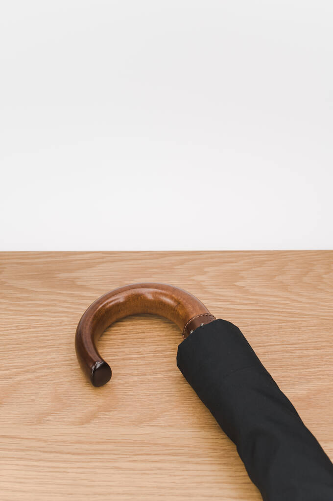 чорна складна парасолька з твердою дерев'яною ручкою на дерев'яній поверхні з копіювальним простором
 - Фото, зображення