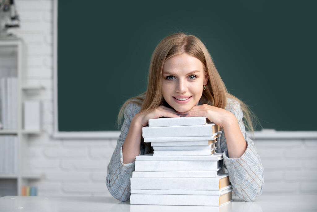 Portrait of female university student study lesson at school or university. Close up portrait of happy attractive young woman student with books on blackboard in classroom. - Photo, Image