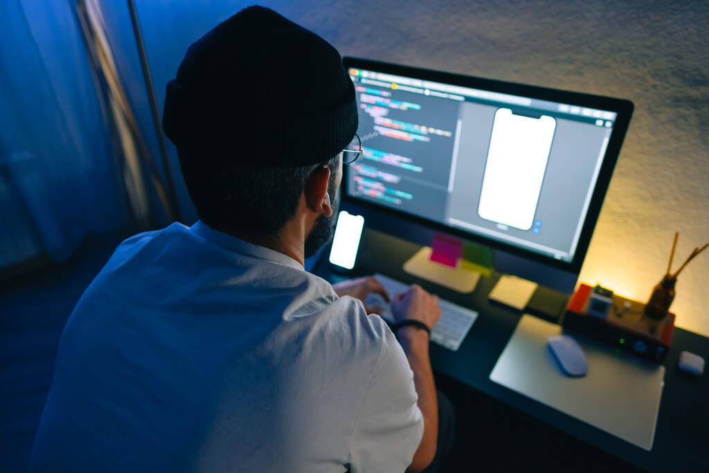 Молодий чоловік мобільний розробник пише програмний код на комп'ютері, програміст працює в домашньому офісі
. - Фото, зображення