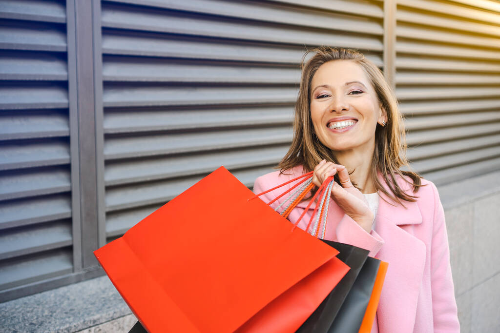 Hübsch lächelnde Frau mit Einkaufstüten im Freien. - Foto, Bild